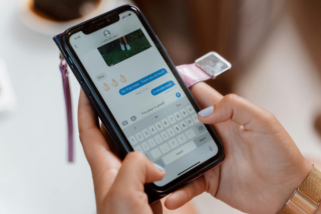 Woman typing on a smartphone, sending a text message with emoji.